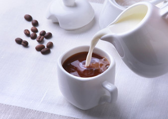 Cup of hot coffee espresso, coffee beans, jug of milk, and bowl with sugar on white background for copy space. Coffee concept.