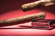 Two Cuban cigars and a lighter on a red background with a light from above