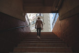 Fototapeta Na drzwi - Young man climbing stairs in pedestrian subway