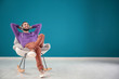 © Africa Studio - Handsome man listening to music while sitting in comfortable armchair against color wall