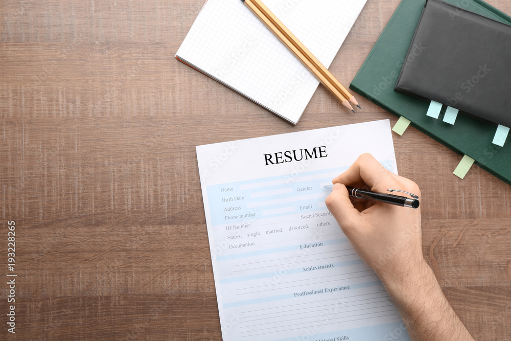 Woman filling in resume form at table. Job interview concept