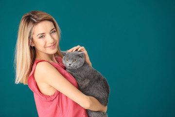 Wall Mural - Young woman with cute pet cat on color background