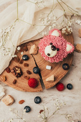 Wall Mural - top view of delicious muffin in shape of bear with berries on wooden board