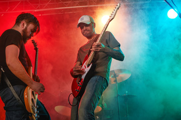 Wall Mural - Rock band performs on stage. Guitarist, bass guitar and drums.