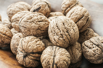 Wall Mural - A pile of whole orgranic walnuts in shell closeup on wooden background