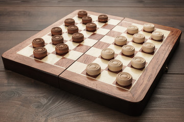 Wall Mural - wooden draughts game on brown table background