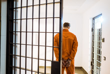 Back View Of Prisoner Standing In Handcuffs In Corridor