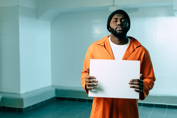 african american prisoner holding blank placard and looking at camera