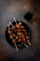 Wall Mural - Grilled beef liver on skewers, with teriyaki or soy sauce, yakitori, dark rusty  table copy space top view