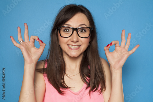 Fotomural Young smiling woman with delicious gesture on blue background