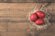 Red easter eggs in nest on wooden background 