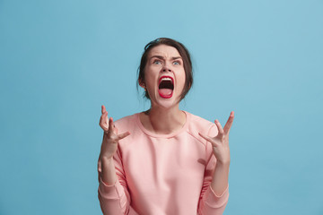 Wall Mural - The young emotional angry woman screaming on blue studio background