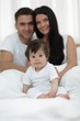 © ASDF - Happy couple and son sitting in bed
