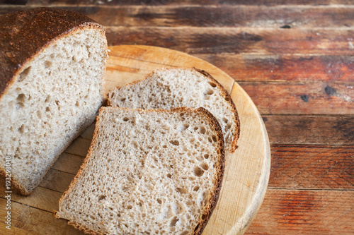 Fotografía Freshly baked sliced bread on a wooden cutting Board on old wooden rustic table