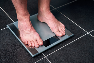 Male feet on the scale in the bathroom