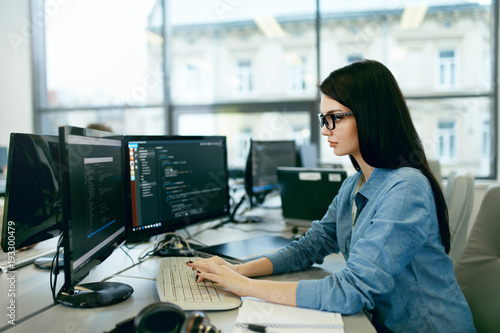 Fotografia Młoda kobieta pracuje i programuje na komputerze w biurze.