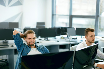 programmers working, looking at computer in it office.