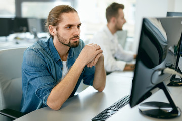 programmers working, looking at computer in it office.