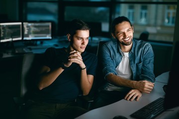 programmers working, looking at computer in office.