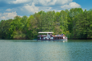 Tourist steamer on a river in the background of forest and green trees, concept of leisure, tourism and lifestyle with copy space