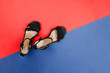 © lavrenkova - Black wedge-heeled sandals on red and blue background. Fashion concept