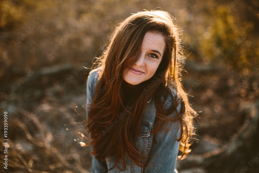 Portrait of a happy young woman with long brown hair and jean jacket ...