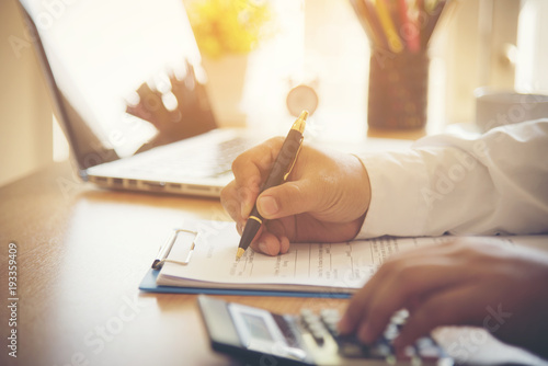 Fotomural Closeup of new homeowner signing a contract of house sale or mortgage papers with a wooden toy house on the document