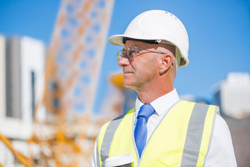 Senior foreman in glasses doing his job at building area on sunny day