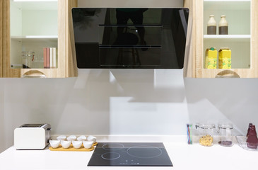 Sticker - Modern kitchen furniture with contemporary kitchenware like hood, black induction stove and oven in house.