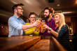 © lordn - Group of young friends in bar drinking beer toasting