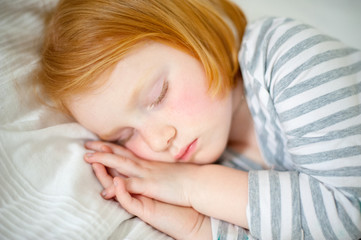 Wall Mural - Red-haired girl sleeps with her hands on her cheek