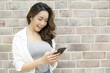 © Jestercine - Asian woman holding smartphone with smiling at wall background. People with technology concept.
