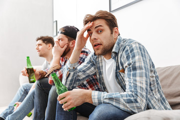 Wall Mural - Photo of adult men 30s being concentrated and uptight watching football match at home with beer in hands