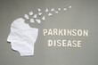 Parkinson's disease concept presented by human head made form white crumpled paper torn on gray background. Creative idea for mental health and neurological disorders.