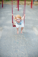 Wall Mural - Girl in a dress on a swing on the playground