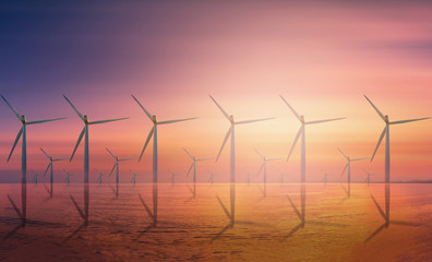 Offshore Wind Turbine in a Wind farm under construction off coast at sunset.