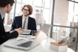 © pressmaster - Successful young economist looking at his colleague during discussion of documents in office
