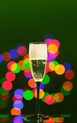 glass full of champagne over holiday lights. Holiday. Party/ Cheers