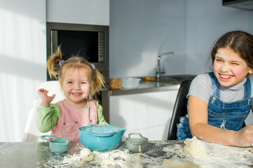 Wall Mural - Two little girls are cooking something in the kitchen.