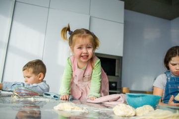 Wall Mural - Three children prepare something from the dough.