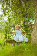 © Kseniia - Happy little blonde caucasian child girl in light blue dress and roses in hair swing on swings in a meadow full of plants red roses yellow chamomiles and dandelions in spring