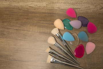 Canvas Print - Closeup shot of beauty blenders, silicone sponges and makeup brushes on a wood background. Space for text