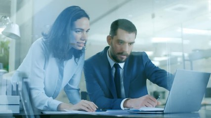 Wall Mural - Beautiful Female Manager Consults Handsome Businessman sitting at His Desk. Both Smile. Working on a Laptop in Modern Office. Shot on RED EPIC-W 8K Helium Cinema Camera.