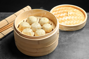 Wall Mural - Bamboo steamer with tasty baozi dumplings on table