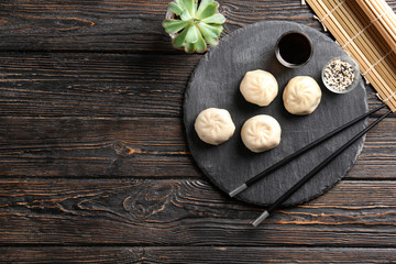 Wall Mural - Slate plate with tasty baozi dumplings, sesame and soy sauce on table