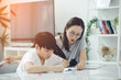 © sirikorn - Asian boy with mother teaching and learning your homework at home