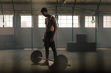 Wall Mural - Man exercising with barbell at gym