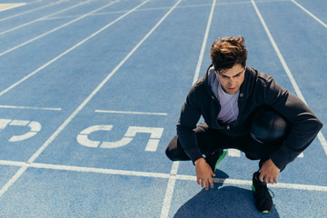 Wall Mural - athlete sitting on the running track with a medicine ball