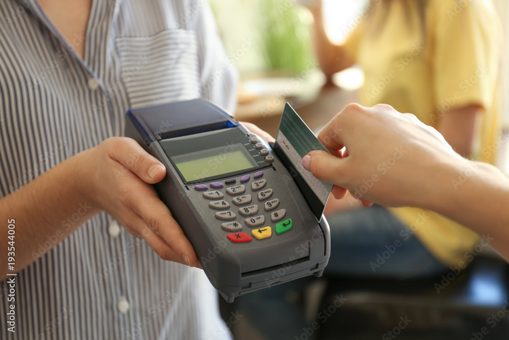 Woman using bank terminal for credit card payment in cafe