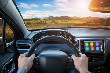 Wall Mural - Driving car using the smart technologies that are displayed on board display. View from the driver's sight on the steering wheel, road and interior.